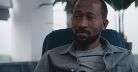 Psychological office: Close up shot of African American adult man sitting in chair, talking to...
