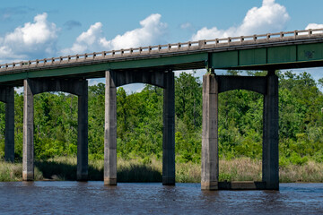 A steel beam bridge spans a river, viewed from beneath.
