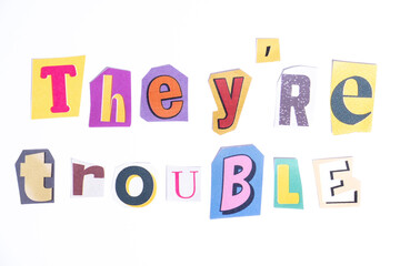 Phrase They're Trouble spelled in cut out newspaper style typography isolated on white background.
