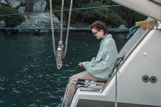 young woman sitting on back pupa of the sailing multihull boat, water background, yachting holiday concept