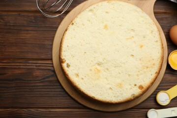 Delicious cut sponge cake and ingredients on wooden table, flat lay