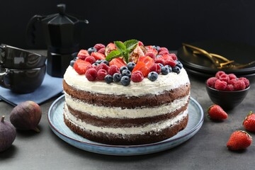 Delicious chocolate sponge cake with berries served on grey table