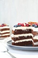 Delicious chocolate sponge cake with berries on white wooden table, closeup