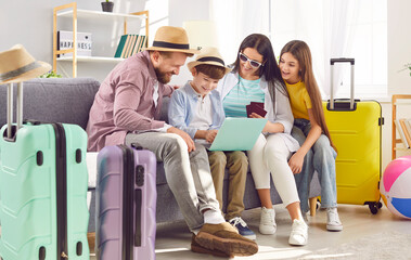 Family mom dad son and daughter sit on sofa browsing laptop booking hotel for their trip bags ready for family vacation. Essence of family vacation sharing excitement of planning together