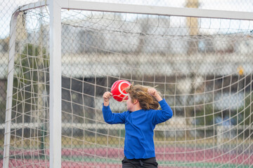 Kid Goalkeeper catches the ball in stadium during a football game. Soccer game moment with kids. Child boy goalkeeper catch soccer ball. Kid goalkeeper with a soccer ball. Goalkeeper training soccer.