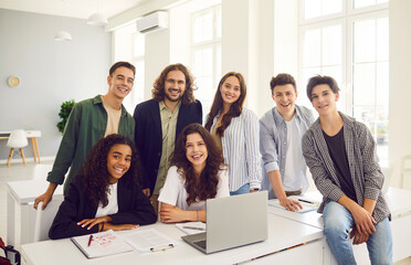 Portrait of a diverse group of happy multinational teenage students during lesson with teacher in a school classroom. Learning reflecting the positive interaction between the students and teacher.