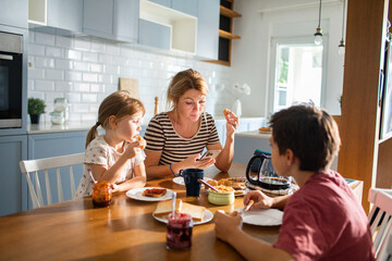 Mother eating breakfast with her kids on kitchen table