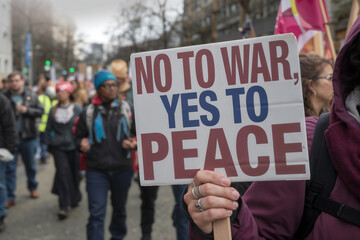 Close-Up of Protester's Hand Holding 'No to War, Yes to Peace' Sign &ndash; Peaceful Protest in the Background
