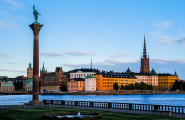 Obraz premium Stunning evening view of Stockholm's waterfront with statues and historic colorful buildings at Gamla Stan island. The serene atmosphere invites exploration and admiration.