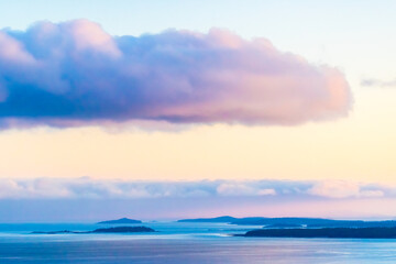 Golden hues blend into the tranquil White Sea as the sun sets, casting a calming glow over distant islands and gentle clouds filling the sky.
