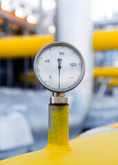 Pressure gauge displayed prominently on gas pipeline machinery in a facility during daylight hours....