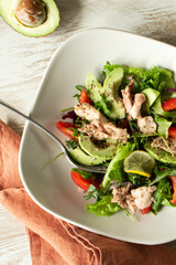 bowl of salad with cod liver, avocado and tomatoes on table