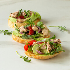 bruschetta with cod liver, avocado and tomatoes on the table