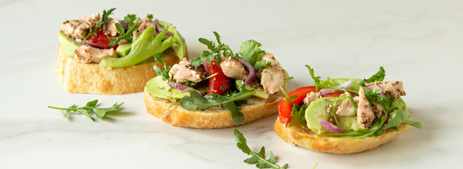 bruschetta with cod liver, avocado and tomatoes on the table