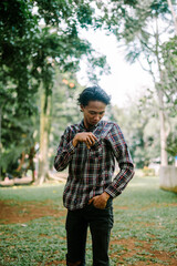 Fototapeta premium Southeast Asian man checking the contents of his shirt pocket, showing curiosity or organization