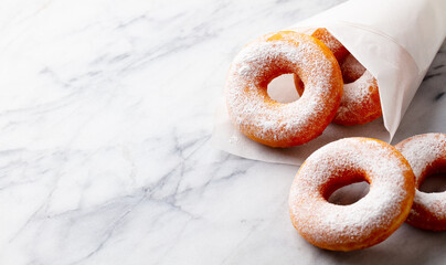 Classic donuts, doughnuts with sugar powder on marble table background. Copy space.