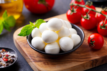 Mozzarella cheese balls with fresh tomatoes and basil. Dark background. Close up.