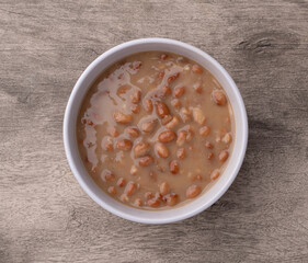 Cooked brown beans in a bowl over wooden table