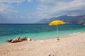 Yellow parasol on the beach in Baska Voda, Croatia