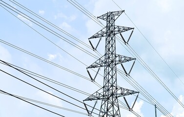 A high-voltage transmission tower stands tall against a backdrop of a cloudy sky. The tower&rsquo;s intricate steel framework supports numerous power lines, which stretch across the scene, carrying electric