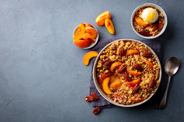 Peach crumble cake with ice cream in bowl. Grey background. Copy space. Top view.