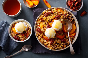 Peach crumble cake with ice cream in bowl. Grey background. Close up. Top view.