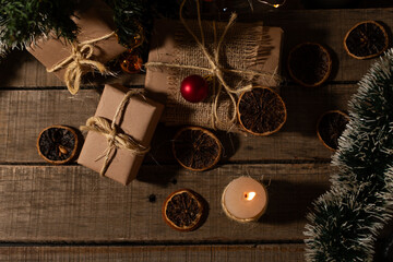 Top view of Christmas gifts and ornaments illuminated by candlelight.