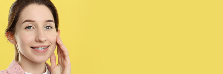 Naklejka premium Beautiful woman with braces smiling on yellow background. Banner design with space for text