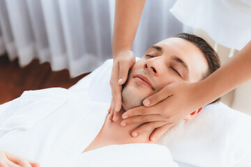 Caucasian man enjoying relaxing anti-stress head massage and pampering facial beauty skin recreation leisure in dayspa modern light ambient at luxury resort or hotel spa salon. Quiescent