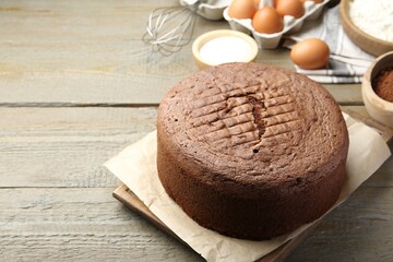 Tasty chocolate sponge cake and ingredients on wooden table, closeup. Space for text