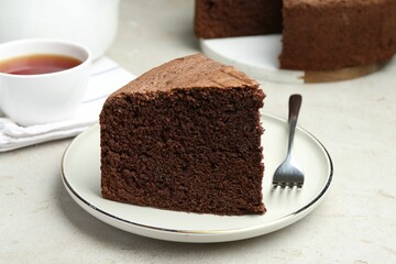 Piece of tasty chocolate sponge cake served on light table, closeup