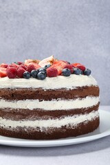 Delicious chocolate sponge cake with berries on light table, closeup