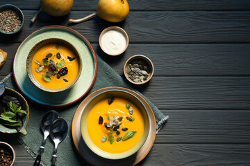 Delicious pumpkin soup served on grey wooden table, top view