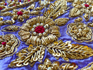 Close up view of The antique golden zardosi border showcases intricate hand-embroidered floral motifs
