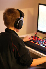 Close up of a teenage boy playing a game on the computer with headphones on © Gosia