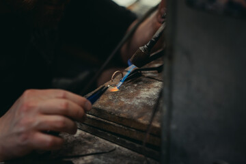 Obraz premium Close-up of a hand of a goldsmith who builds a precious jewel with valuable diamonds. To make the jewel it takes: precision, craftsmanship and patience. Concept of: gold, luxury.