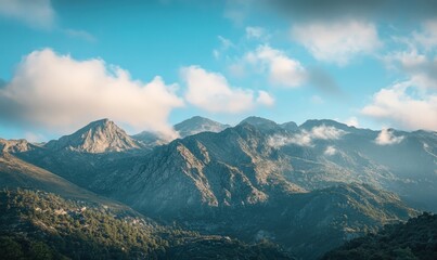Naklejka premium Majestic mountain range with fluffy clouds in a blue sky.