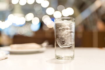 A glass of cold water with ice cube and bokeh background
