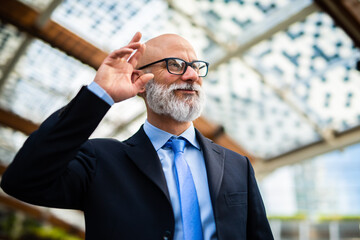 Senior businessman fixing hair while smiling outdoors