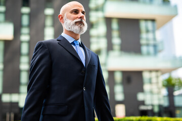 Confident senior businessman standing outside office building looking up