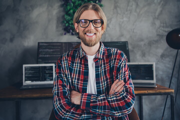 Portrait photo of blond hair confident it specialist folded hands wearing checkered shirt near his...