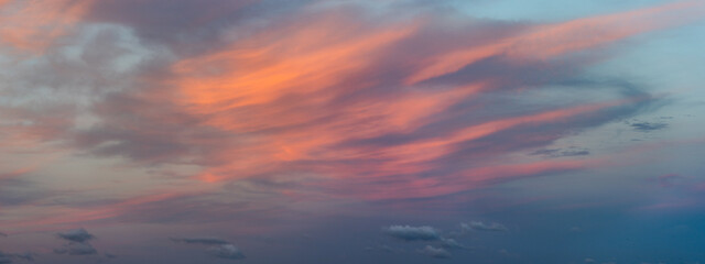 Fototapeta premium A panoramic view of a sky during sunset with vibrant clouds spread across the horizon, giving a dramatic and peaceful atmosphere.