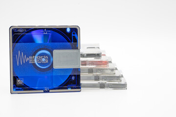 Close-up of a blue minidisc together with others inside their cases isolated on white background