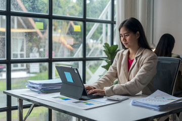 Young asian businesswoman working on tablet computer in modern office