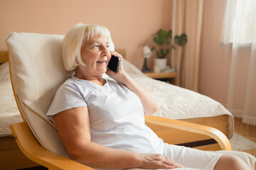 Portrait of attractive successful elderly woman using mobile talking on a cellphone while relaxing at home.