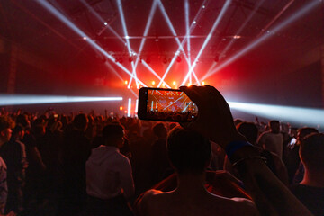 Hands holding phone and making photos on the concert.