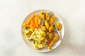 Savor the crispy fried zucchini flowers in batter, a savory cauliflower omelette with stewed peppers, and a vibrant fresh mixed green salad for a wholesome, nutritious meal
