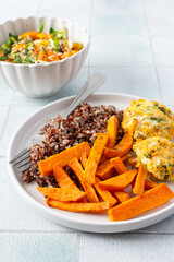 A healthy and filling meal of brown rice, baked sweet potato and squash chickpea pancakes, packed with flavor and nutrients, fresh salad of tomatoes and cucumbers