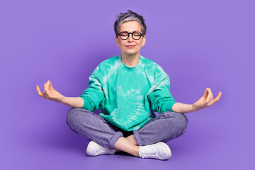 Full size photo of pretty retired female sit floor meditate wear trendy green outfit isolated on...