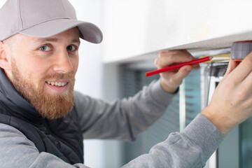 service man installing window with screwdriver